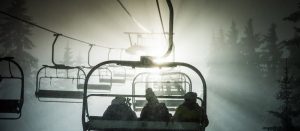 Tre skikjørere i stolheis La Clusaz i Alpene